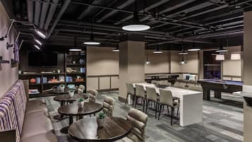 Un moderno área de lounge con diversas opciones de asientos, mesa de billar y bar.
