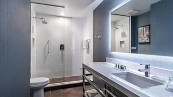 Een moderne badkamer met een douchecabine van glas, een wit toilet en een wastafel met een grote spiegel.