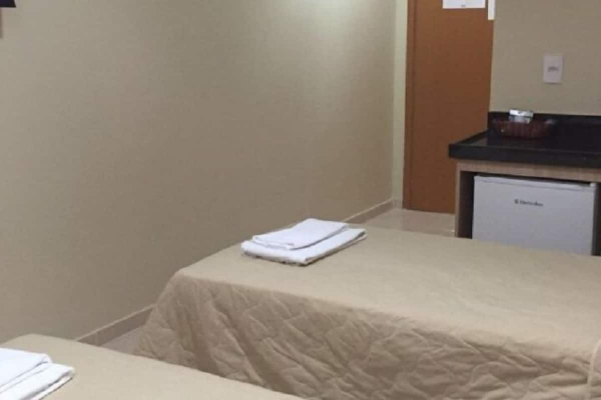 A hotel room with a bed, a small table, and a minibar.
