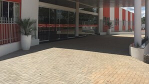 En moderne bygning med et overdækket indgangsparti, store vinduer og et belagt område med plantekasser.