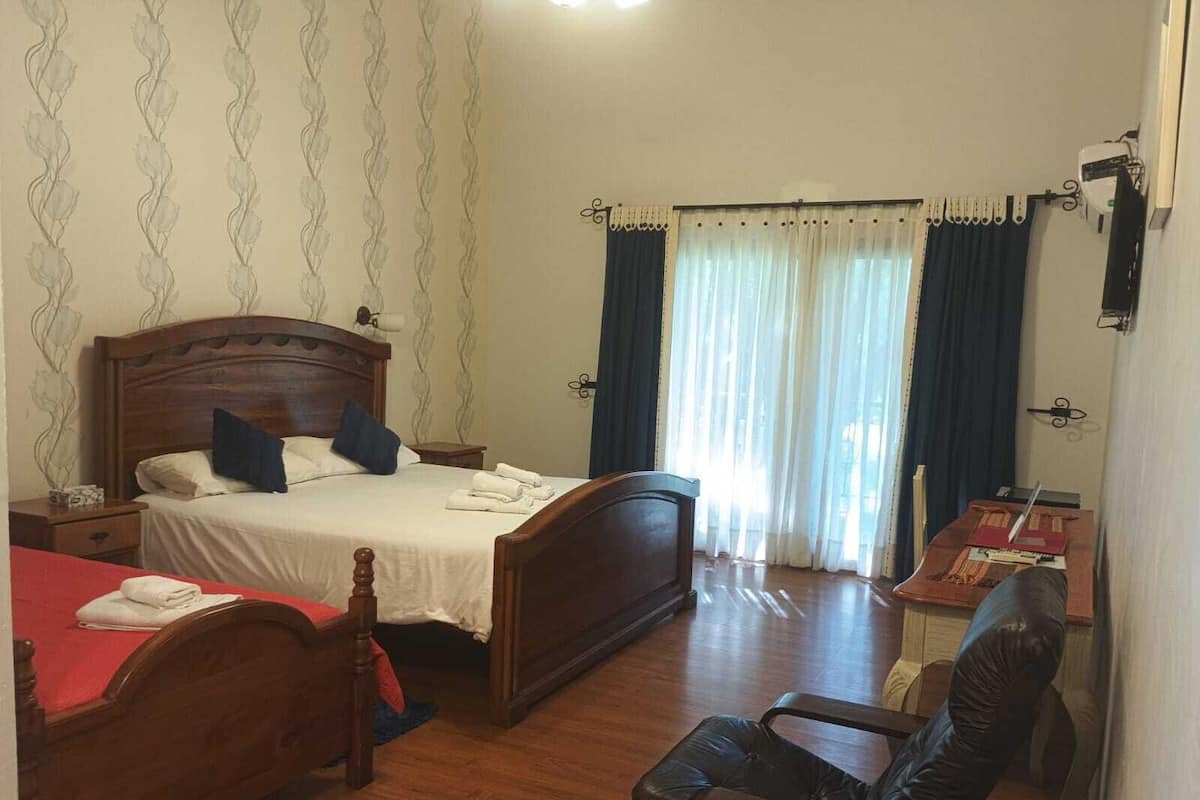 A hotel room with a wooden bed, a desk, a chair, and a window with curtains.