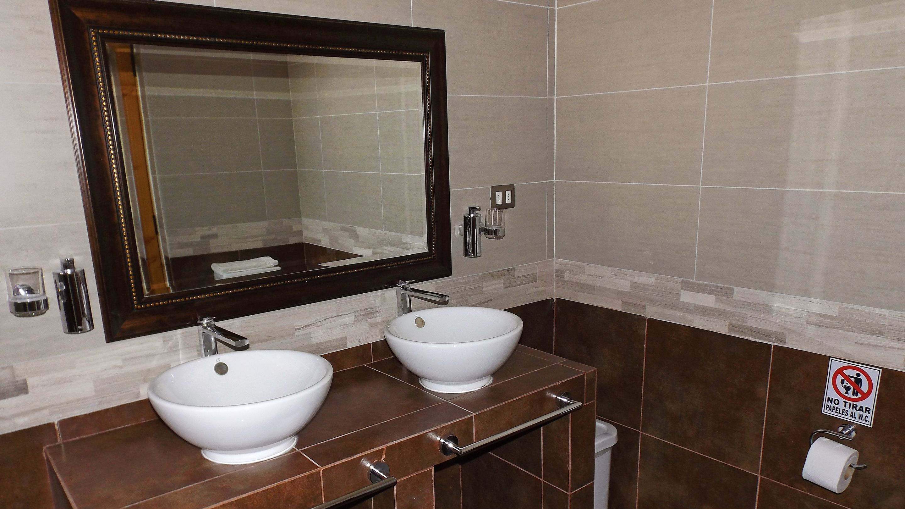 A bathroom with two white sinks, a large mirror, and a towel rack.
