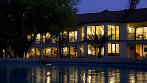 Ett hotell med flera våningar, balkonger, stora fönster och en swimmingpool på förgrunden.