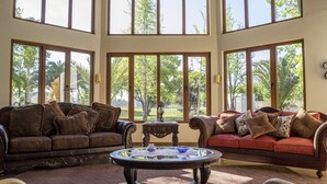 Ett rymligt vardagsrum med två soffor placerade framför ett stort fönster med utsikt över en trädgård.