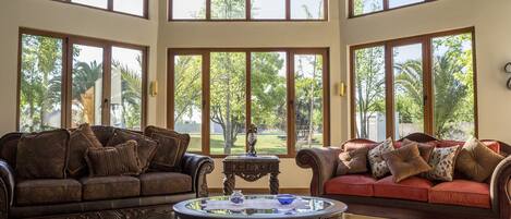 A spacious living room with two sofas facing a large window overlooking a garden.