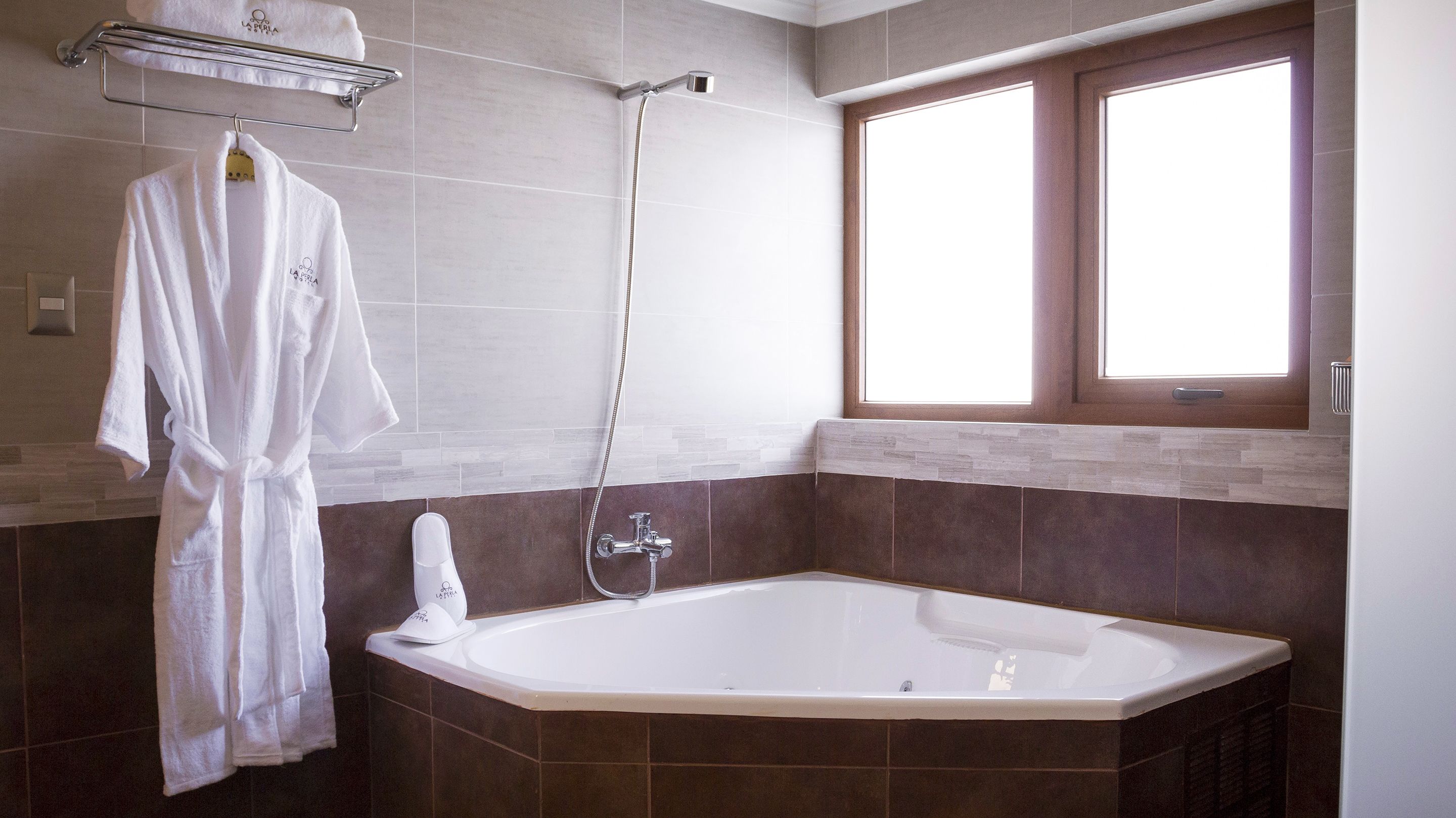 Une salle de bain moderne dotée d’une grande baignoire, d’une douche et d’une fenêtre laissant entrer la lumière naturelle.