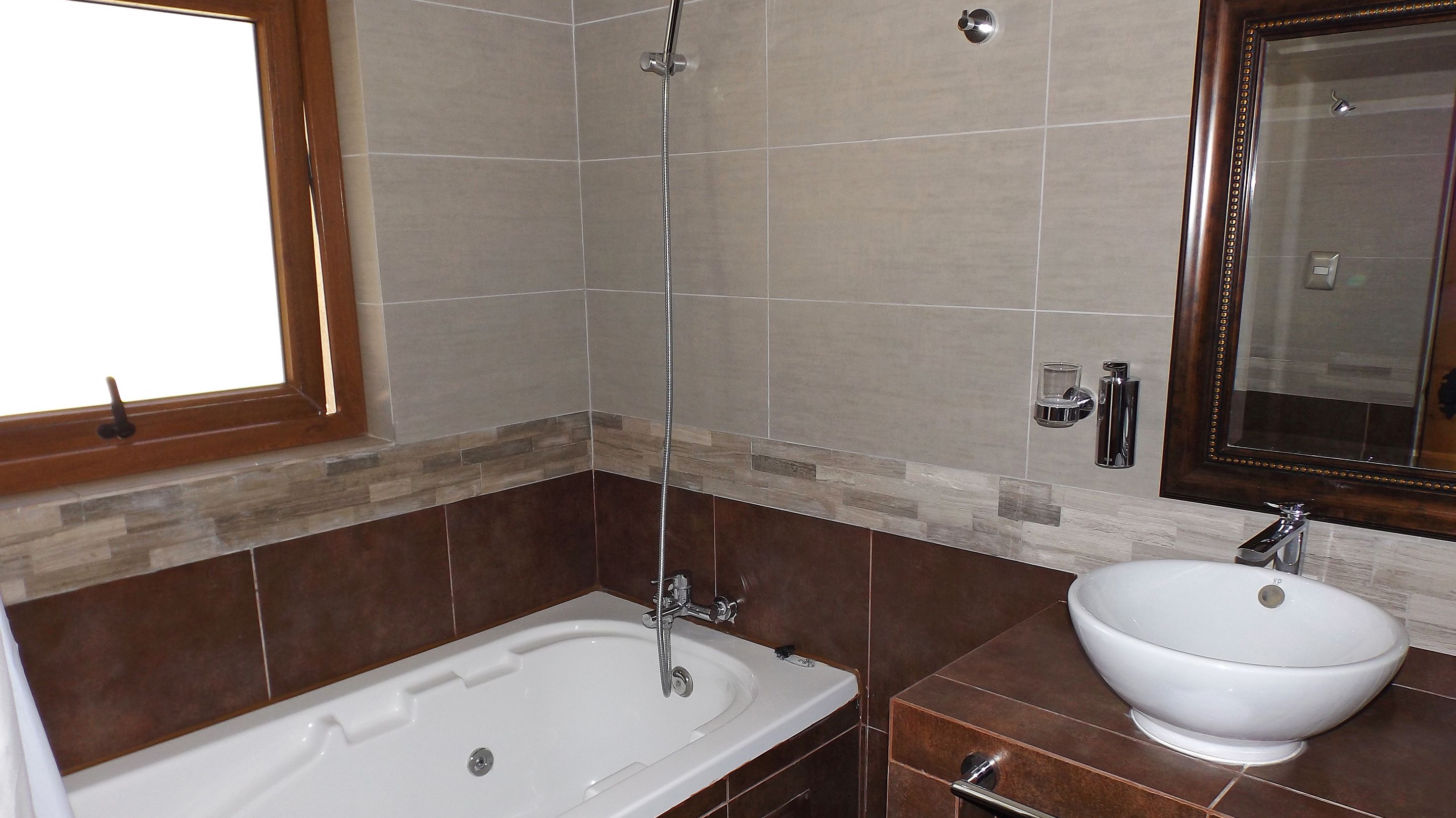 Een badkamer met een bad, een wastafel, een spiegel en een douche.