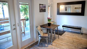 A room with a wooden floor, a dining table with chairs, a bench, a potted plant, and a large mirror on the wall. - The Francis Boutique Inn (Ucluelet)