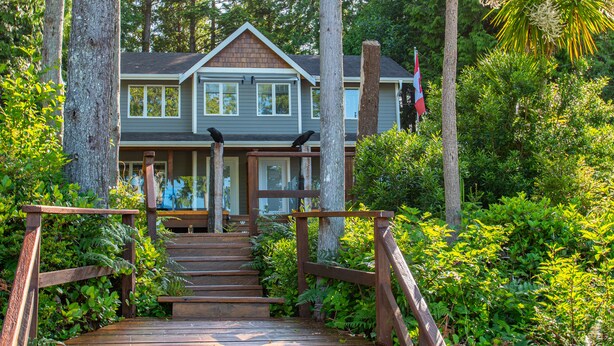 A two-story house with a wooden staircase leading to a front porch. - The Francis Boutique Inn (Ucluelet)