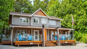 A two-story house with a porch, a covered deck, and a flagpole. - The Francis Boutique Inn (Ucluelet)