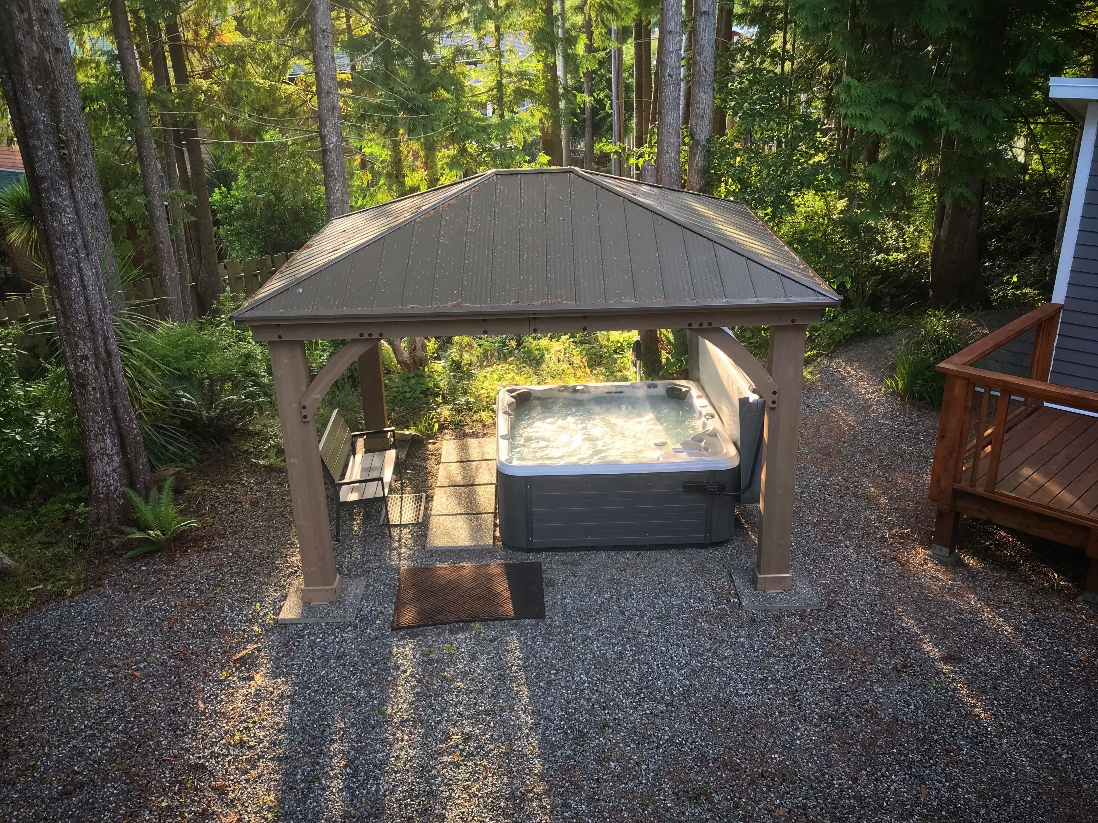 A hot tub under a wooden gazebo surrounded by trees.