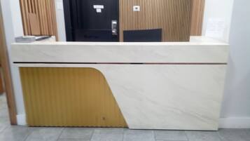 Taulell de recepció amb panell de fusta i mostrador de marbre.