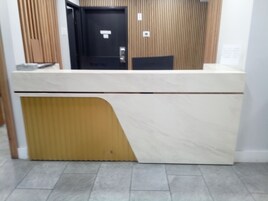 Un mostrador de recepción con panel de madera y encimera de mármol.