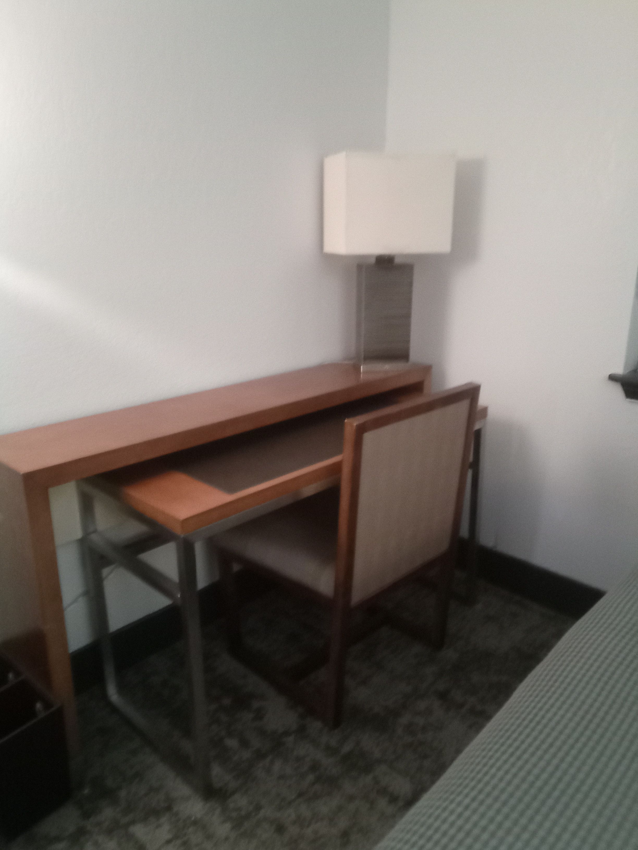 A compact room with a desk, chair, and a lamp.