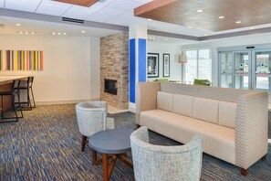 A hotel lobby with a seating area, a fireplace, and a patterned carpet. - Holiday Inn Express & Suites Chadron by IHG (Chadron)