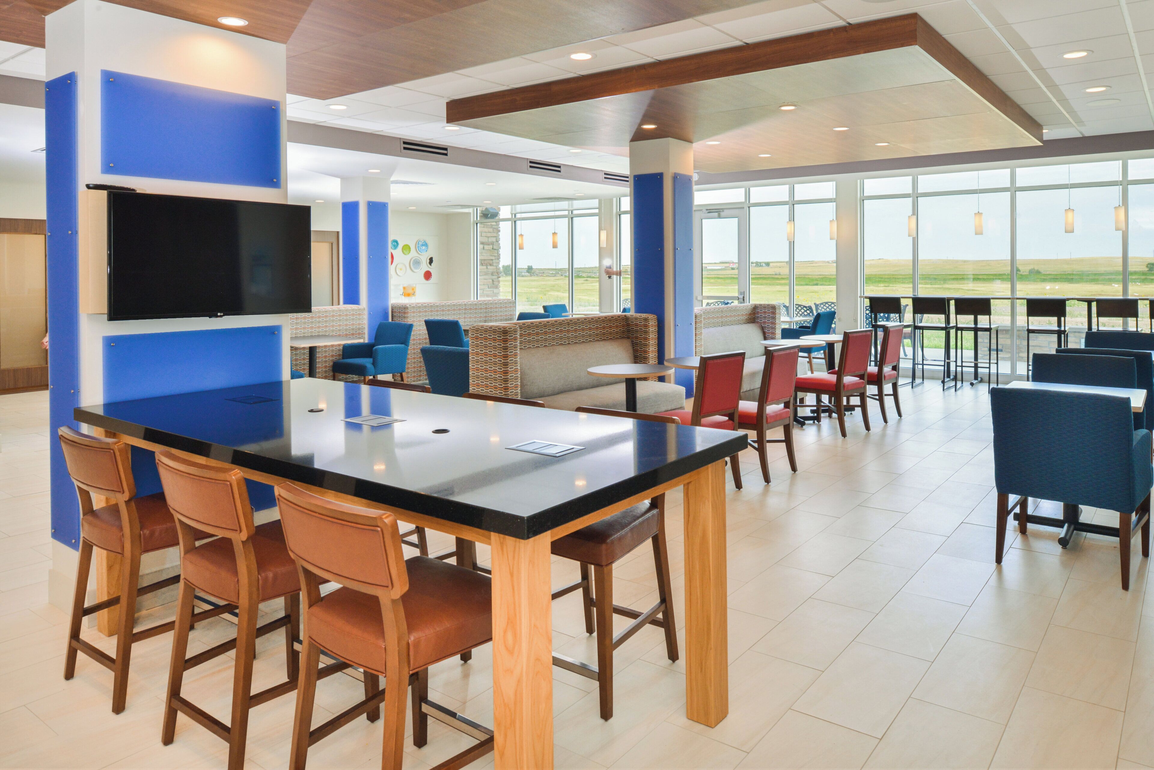 A modern indoor space with a bar area, seating, and large windows offering a view.