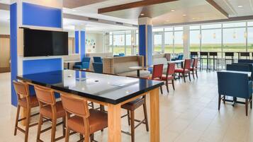 A modern indoor space with a bar area, seating, and large windows offering a view.