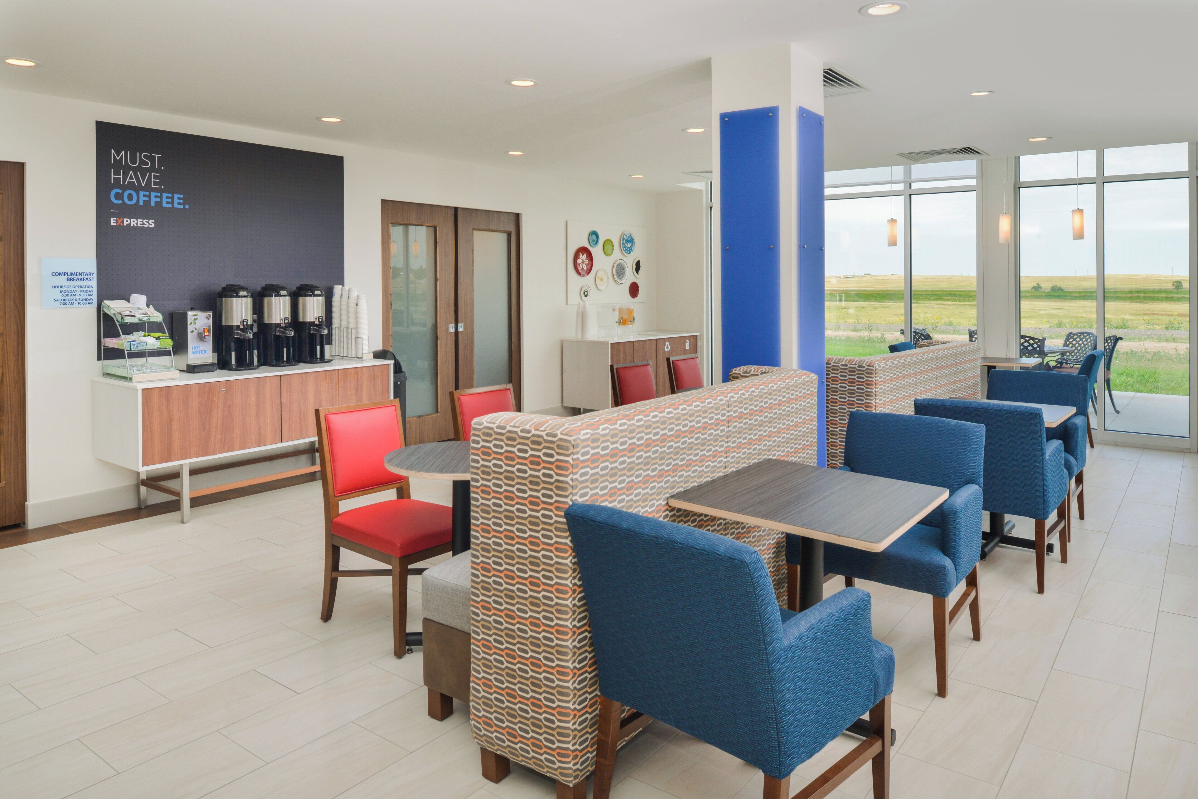 A modern cafe with a coffee station, seating area, and large windows offering a view.