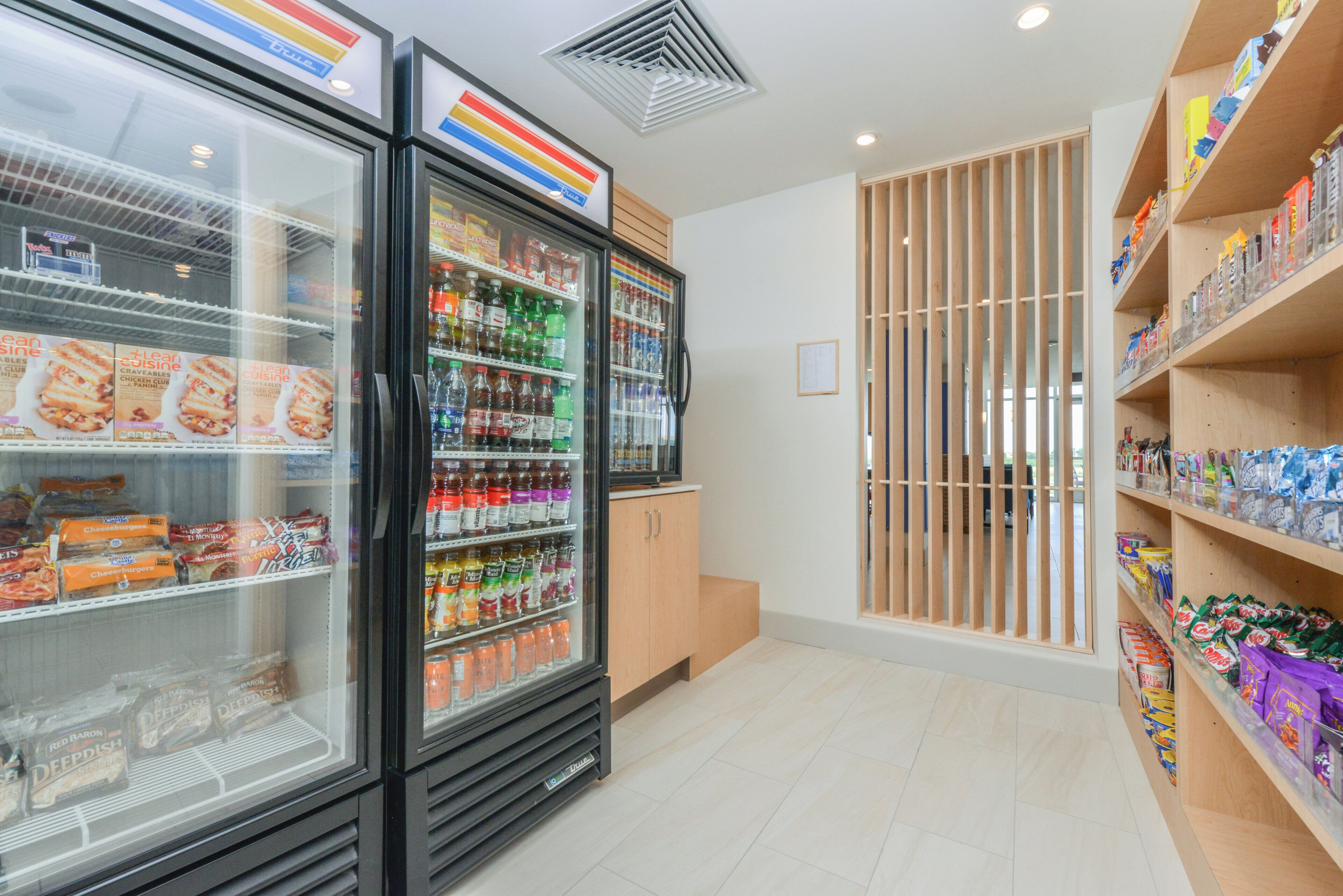 Un présentoir réfrigéré contenant divers produits alimentaires et un réfrigérateur pour boissons.