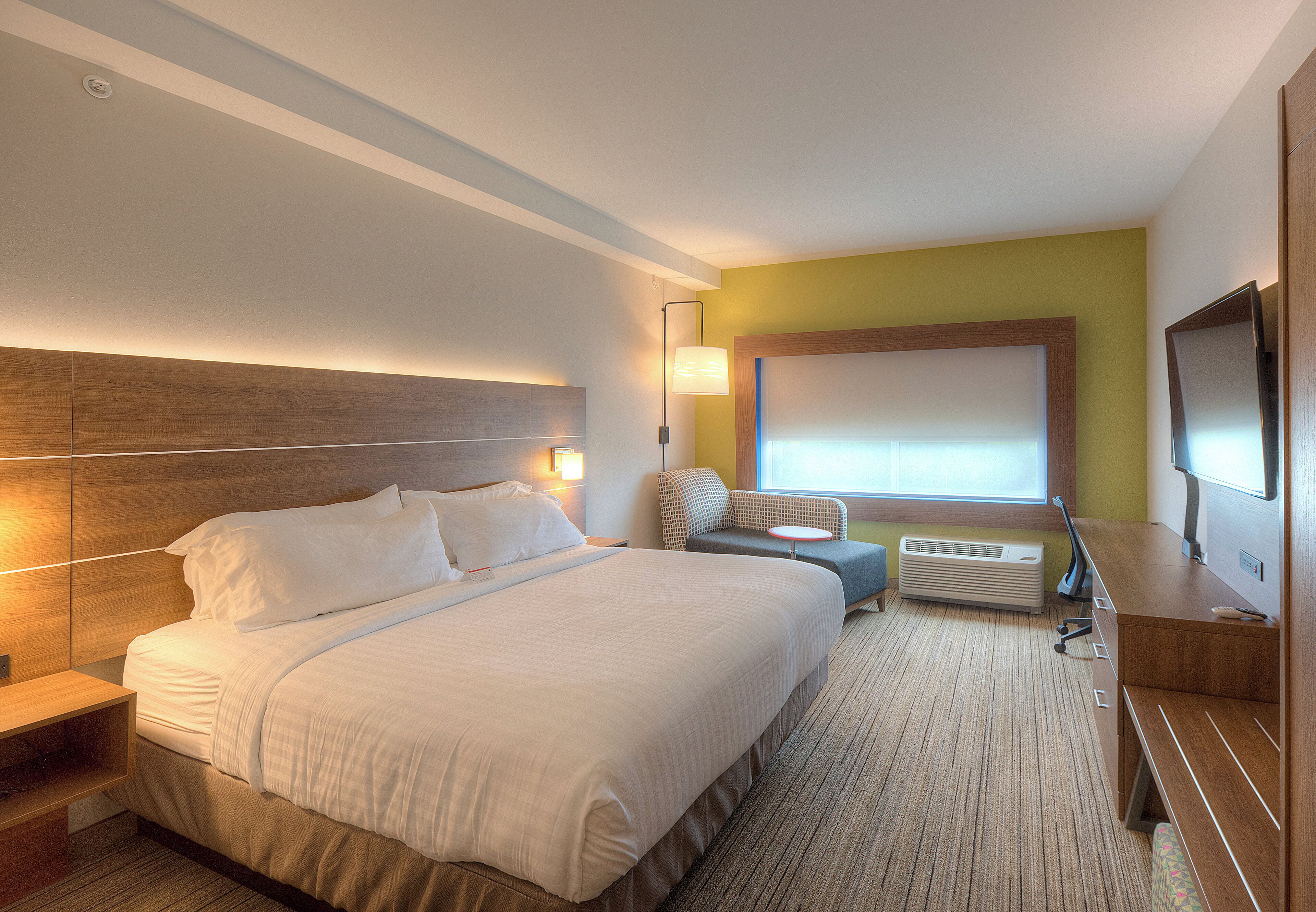 Una habitación de hotel con una cama grande, un escritorio, una silla, un televisor y una ventana.