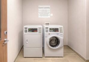 Vieraiden käytössä oleva pyykinpesutila, jossa on kaksi pesukonetta ja opastekyltti, jossa on ohjeet laitteiden käyttöön.