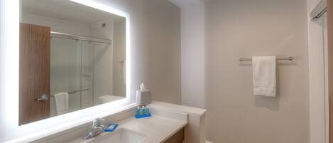 A bathroom with a large mirror, a sink, a toilet, and a towel rack.