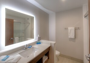 Un baño con un espejo grande, un lavabo, un inodoro y un perchero para toallas.