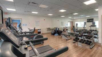 Ein Fitnessstudio mit Laufbändern, Kurzhanteln und Trainingsgeräten.