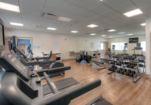 Un centre de remise en forme équipé de tapis de course, d’haltères et d’appareils d’exercice.