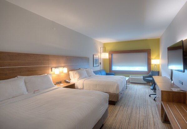 Una habitación de hotel con dos camas, un escritorio, una silla, un televisor y una ventana.