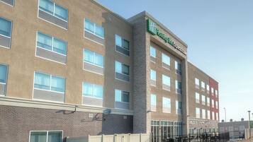 Ein Holiday Inn Express Hotel mit vielen Fenstern, einer Ziegel-Fassade und einem umzäunten Außenbereich mit Tischen und Stühlen.