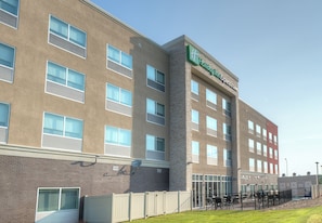 A Holiday Inn Express hotel with multiple windows, a brick facade, and a fenced outdoor area with tables and chairs. - Holiday Inn Express & Suites Fort Mill by IHG (Fort Mill)