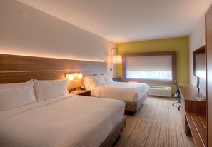 Habitación de hotel con dos camas, un escritorio, una lámpara y un ventanal grande.