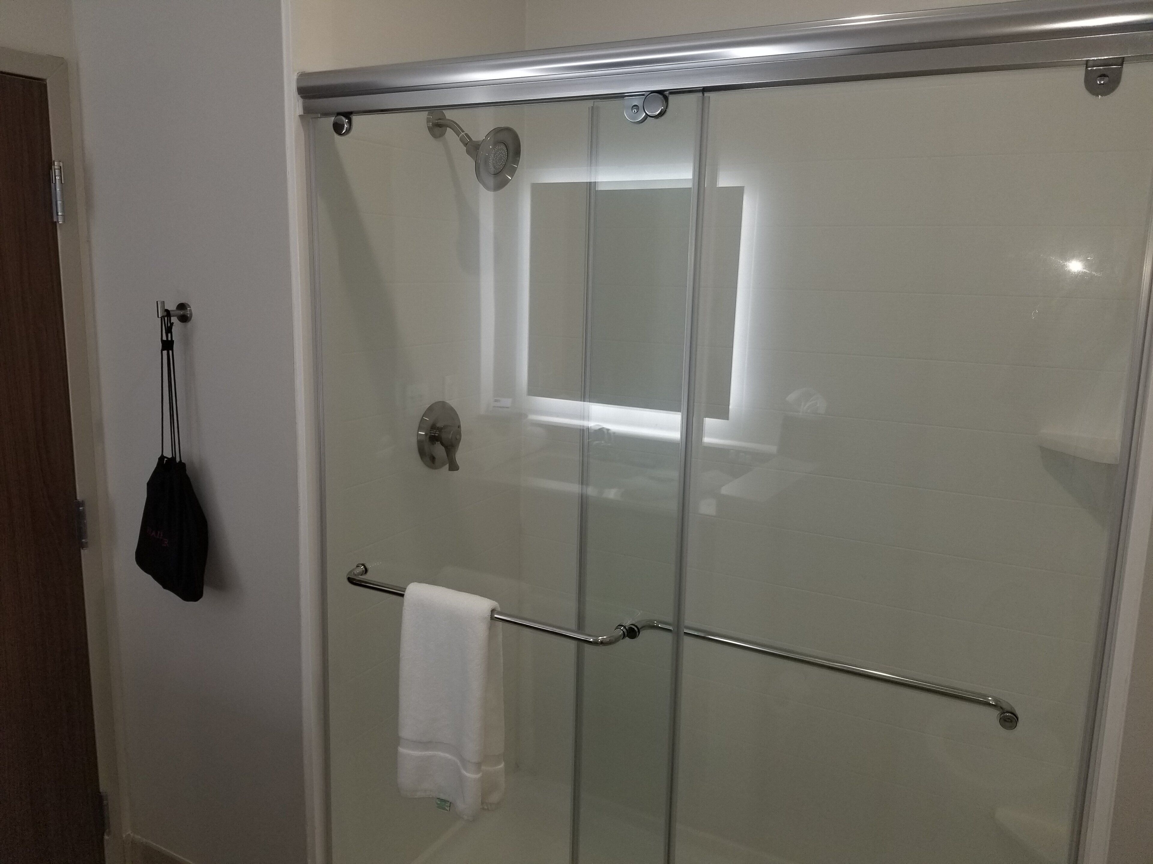 A glass-enclosed shower with a towel rack and a door handle.
