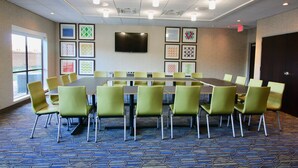 A conference room with a long table, green chairs, a flat-screen TV, and framed artwork on the walls. - Holiday Inn Express & Suites Kirksville - University Area by IHG (Kirksville)