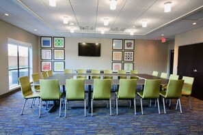 A conference room with a long table, green chairs, a flat-screen TV, and framed artwork on the walls. - Holiday Inn Express & Suites Kirksville - University Area by IHG (Kirksville)