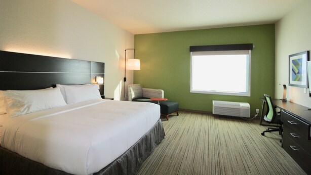 A hotel room with a large bed, a desk, a chair, a small table, a lamp, and a window. - Holiday Inn Express & Suites Kirksville - University Area by IHG (Kirksville)