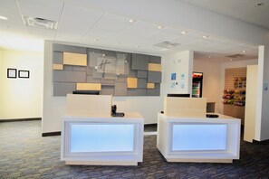 A reception area with two reception desks, a wall-mounted sign, and a vending machine. - Holiday Inn Express & Suites Kirksville - University Area by IHG (Kirksville)