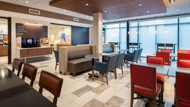 A modern cafe with a seating area featuring tables and chairs, a coffee station, and a large window providing natural light. - Holiday Inn Express & Suites Camas - Vancouver by IHG (Camas)