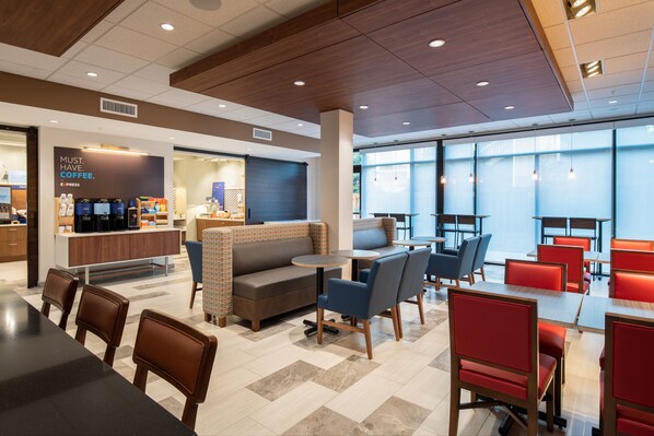 A modern cafe with a seating area featuring tables and chairs, a coffee station, and a large window providing natural light. - Holiday Inn Express & Suites Camas - Vancouver by IHG (Camas)