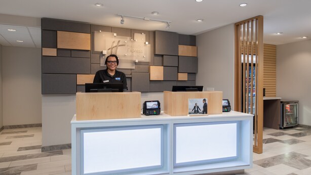 A reception desk with a modern design, a digital screen, and a wooden partition. - Holiday Inn Express & Suites Camas - Vancouver by IHG (Camas)