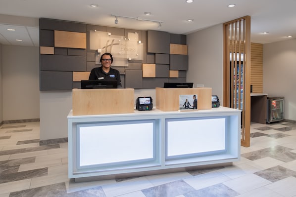 A reception desk with a modern design, a digital screen, and a wooden partition. - Holiday Inn Express & Suites Camas - Vancouver by IHG (Camas)