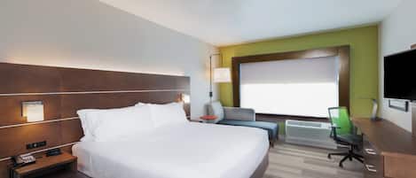 Habitación de hotel con una cama grande, un escritorio, una silla, un televisor y una ventana con vistas.