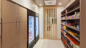 A narrow hallway with wooden cabinets on one side and shelves stocked with various food items on the other. - Holiday Inn Express & Suites Chanute by IHG (Chanute)
