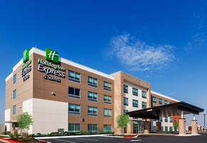 A Holiday Inn Express & Suites building with a modern design, featuring multiple floors, large windows, and a covered parking area.