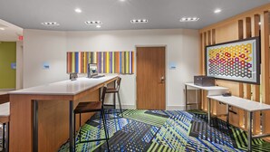 Un espace de bureau moderne avec une longue table, des chaises et un tableau abstrait aux couleurs vives accroché au mur.