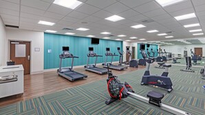 Une salle de sport équipée de tapis de course, de vélos elliptiques et d’un vélo d’appartement.