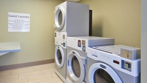 Un espace buanderie à la disposition des clients, équipé de plusieurs machines à laver et agrémenté d’un panneau indiquant les consignes d’utilisation.
