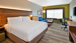 A hotel room with a large bed, a desk, a chair, a sofa, and a window with a view. - Holiday Inn Express & Suites South Hill by IHG (South Hill)