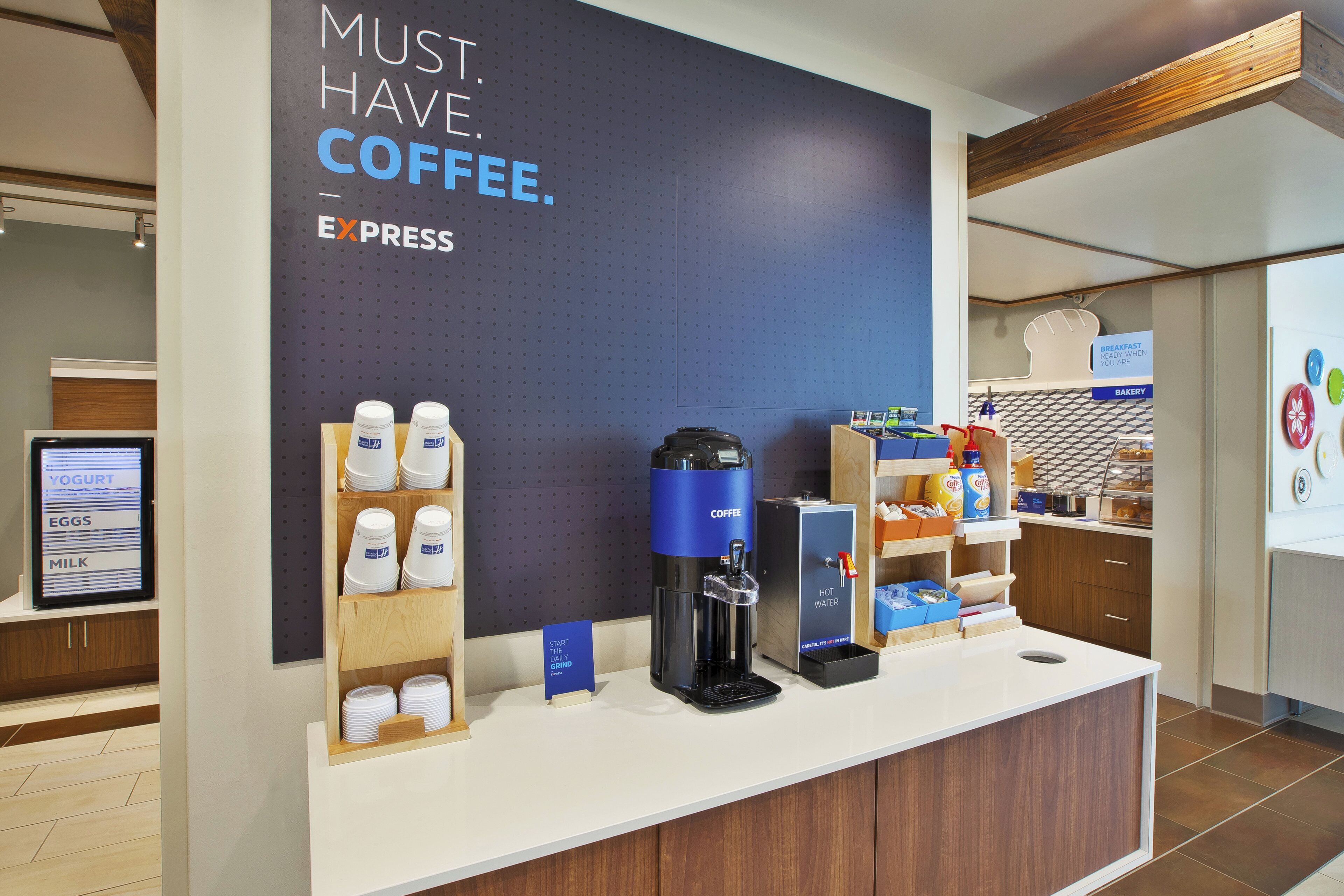 Eine Kaffeestation mit einem Schild, auf dem 'MUST. HAVE. COFFEE.' steht, und einer Kaffeemaschine.